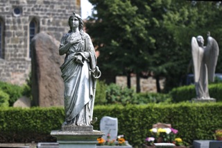 Bild: Pieta auf dem Wipertifriedhof zu Quedlinburg. Im Hintergrund ist die Wipertikirche zu sehen.