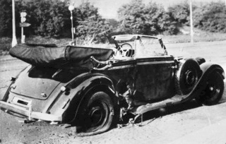 Bild: Der beschädigte Wagen Reinhard Heydrichs nach dem Attentat. Under the licence of Commons:Bundesarchiv. Bundesarchiv, Bild 146-1972-039-44 / unknown / CC-BY-SA.