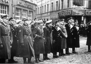 Bild: Aufmarsch der SS zum ersten Jahrestag des EISLEBER BLUTSONNTAGES. Der zweite von rechts ist der NSDAP Kreisleiter Ludolf von Alvensleben. Dieses Bild ist gemeinfrei, weil seine urheberrechtliche Schutzfrist abgelaufen ist.